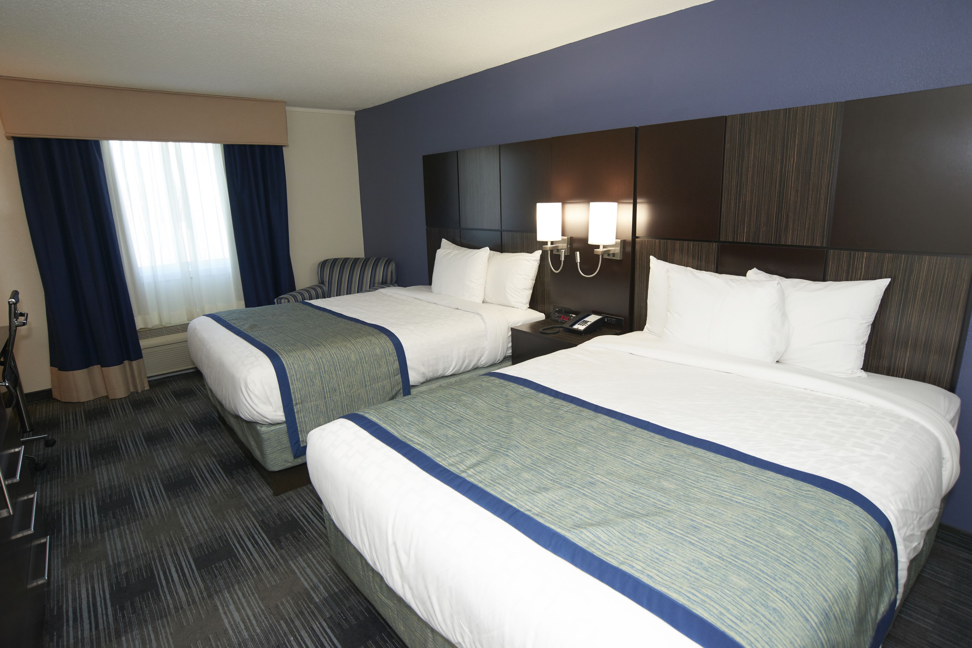 A hotel room with two beds, a desk, and a chair.