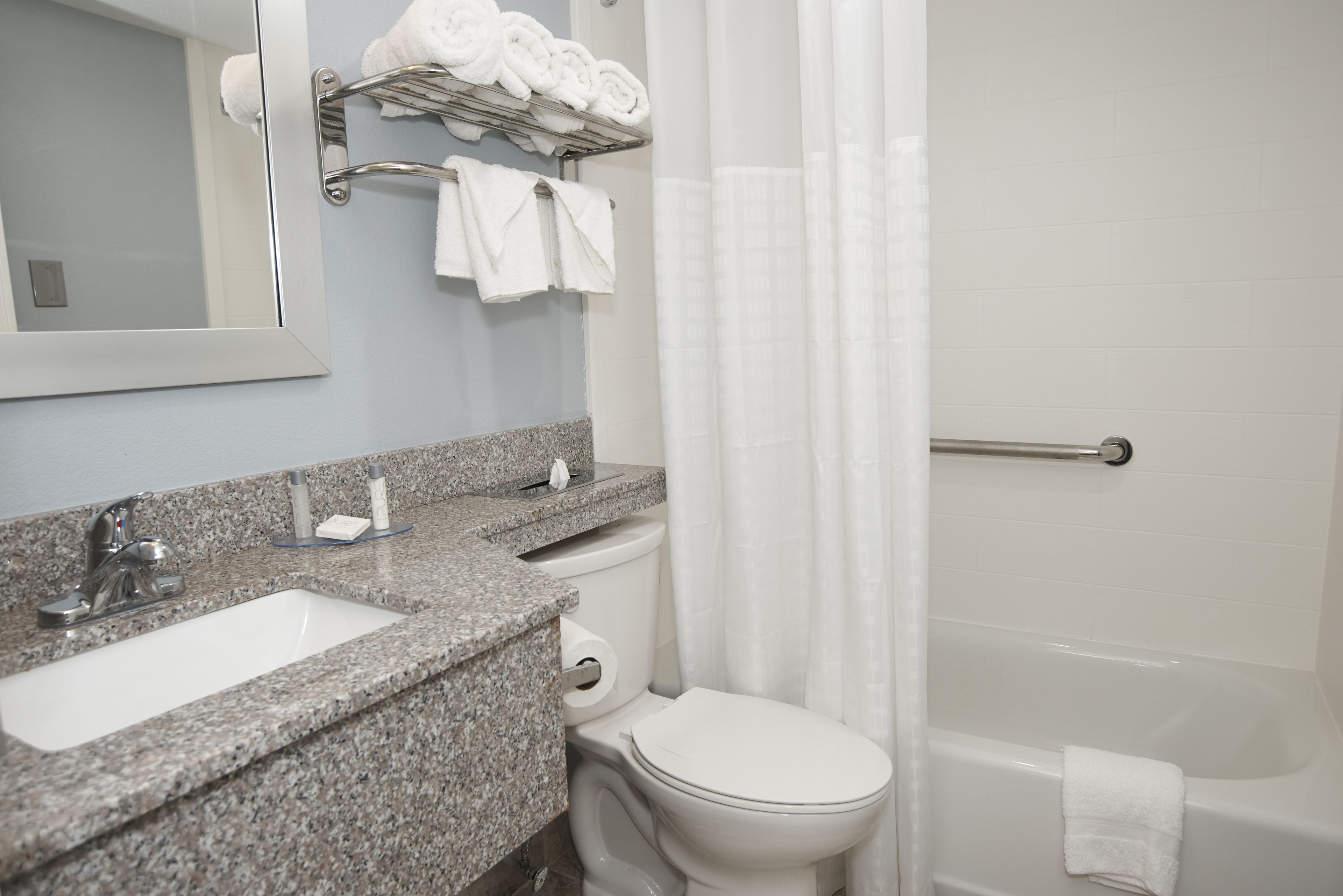 A bathroom with a granite countertop sink, a toilet, and a bathtub.