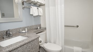 A bathroom with a granite countertop sink, a toilet, and a bathtub.