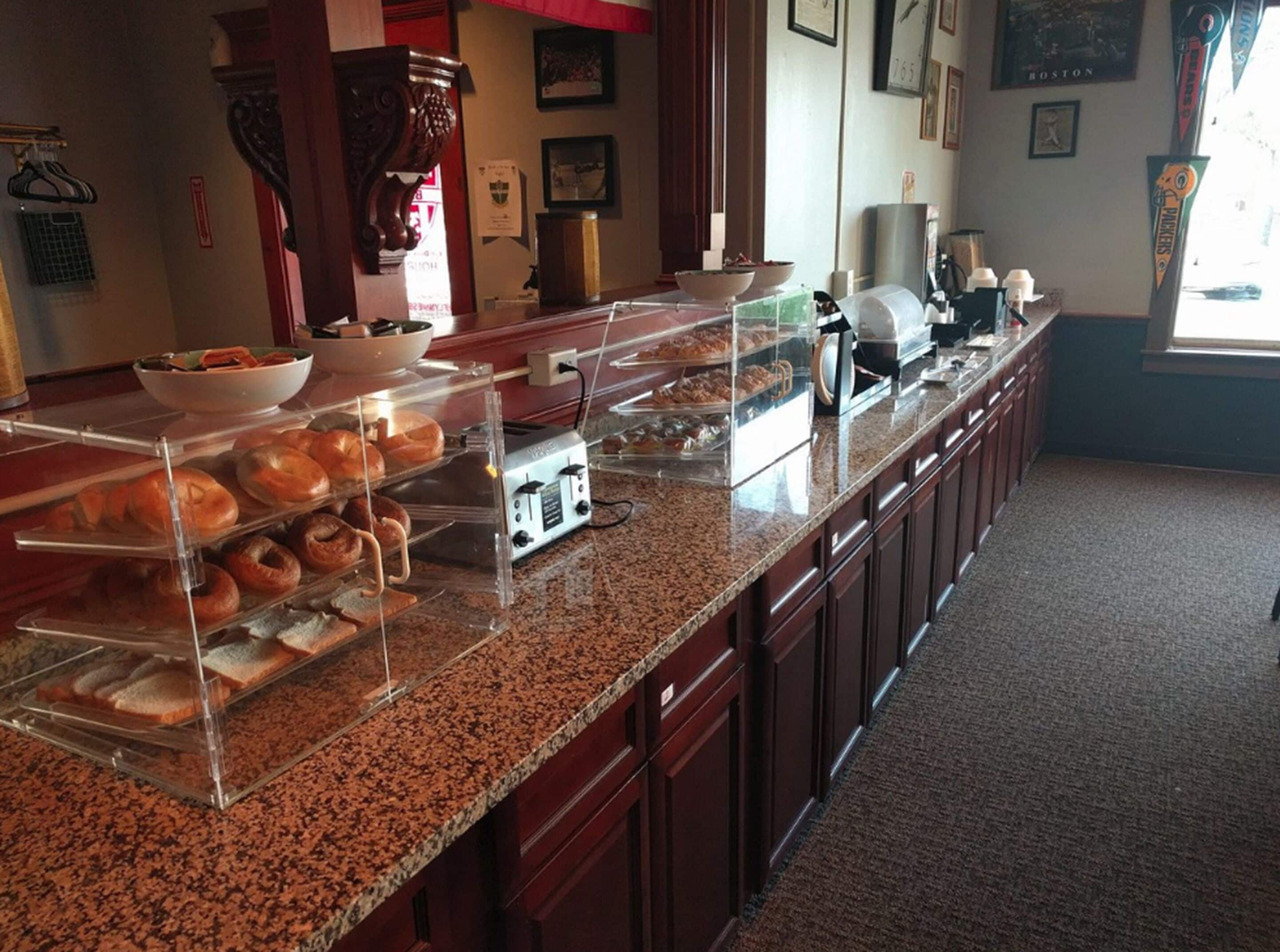 Una barra de desayuno con diversos pasteles y pan exhibidos en vitrinas.