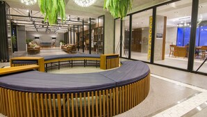 Un espacio interior moderno con una zona de estar circular, detalles de madera y plantas verdes colgantes.