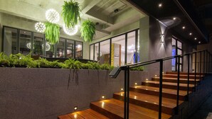 Una escalera moderna con peldaños de madera y baranda de metal, que conduce a una habitación con un amplio ventanal y un letrero que dice "ROSSOTTO".