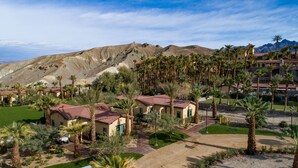 A resort with multiple buildings, palm trees, and a mountainous backdrop.