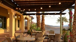 An outdoor patio with wicker furniture and a pergola.
