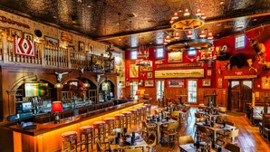 A bar area with a long counter, multiple stools, and a variety of mounted animal heads on the walls.