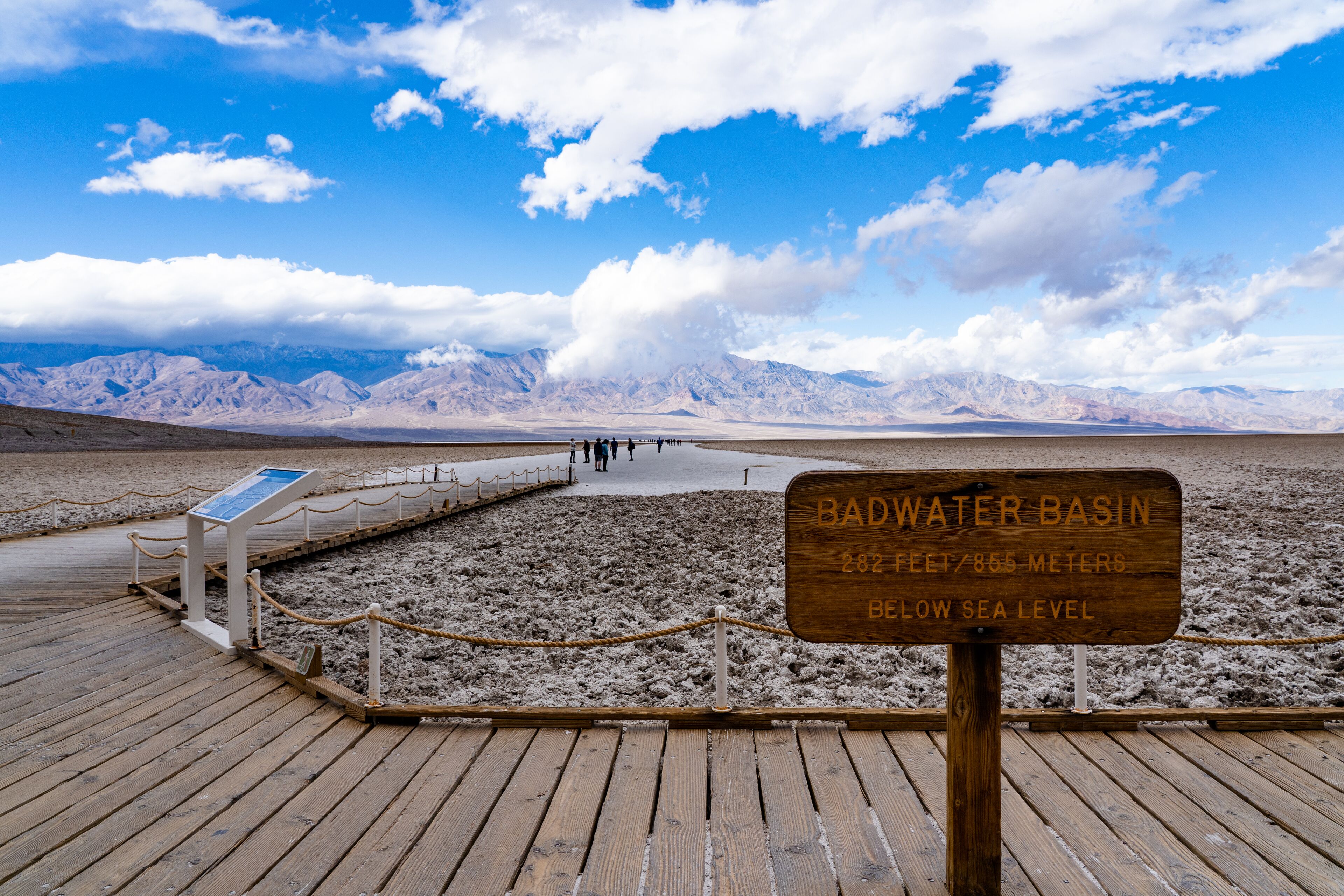 A wooden boardwalk leading to a viewing area with a sign indicating the Badwater Basin's elevation below sea level.
