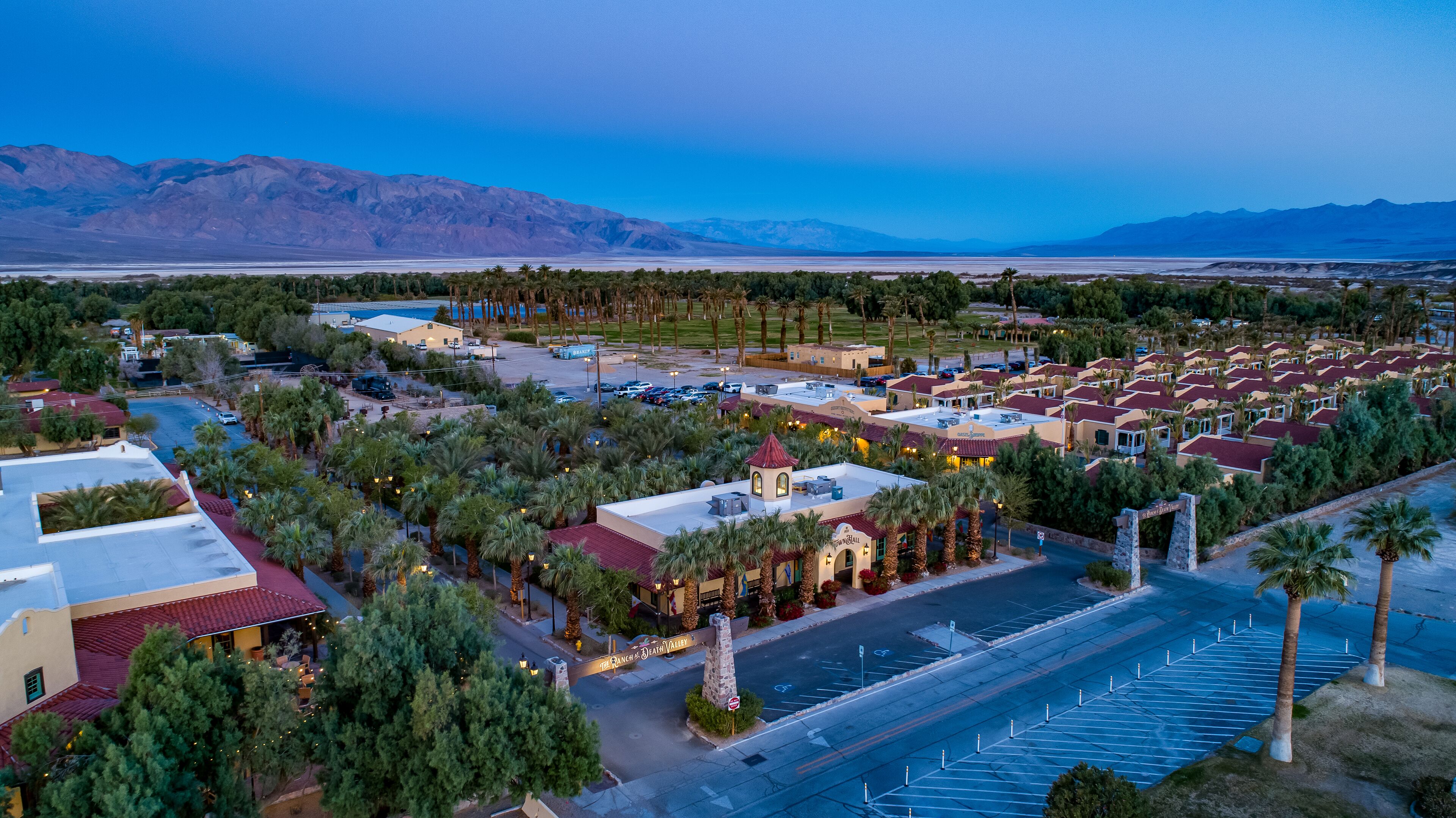 An aerial view of a resort with multiple buildings, palm trees, and a parking lot.