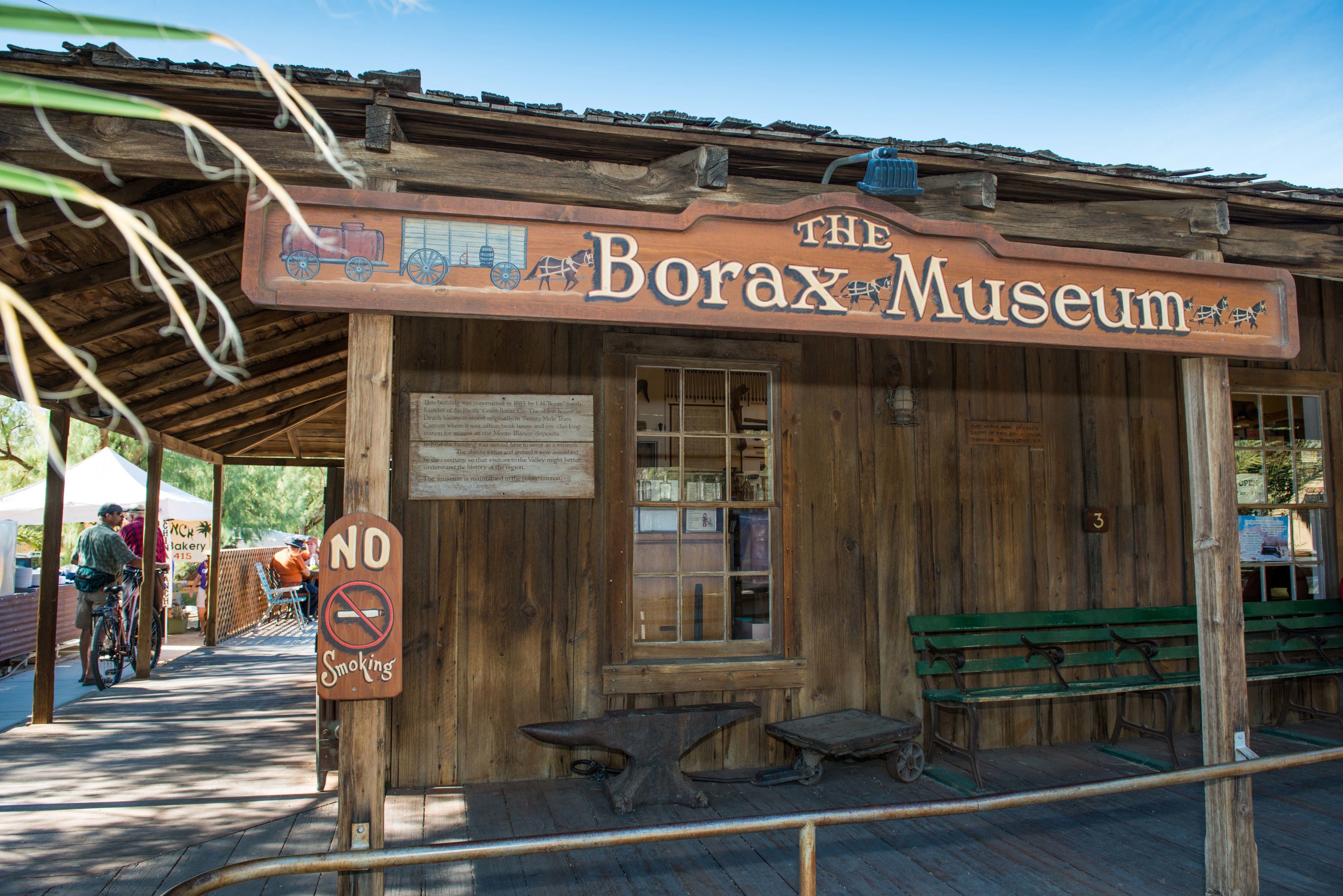 A wooden building labeled "The Borax Museum" with a no smoking sign, benches, and a covered area with a table.