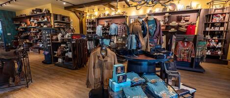 A store with various clothing items, accessories, and a display of hats and bags.