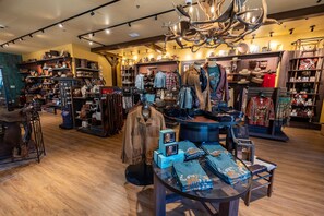 A store with various clothing items, accessories, and a display of hats and bags.