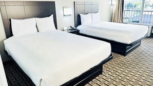 A hotel room with two beds, a bedside table with a phone, and a view of the city through the window. - Fiddler's Inn (Nashville)