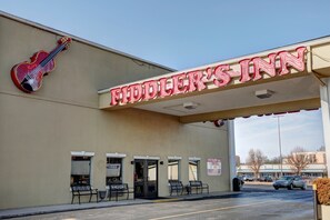 A building with a sign reading "Fiddler's Inn" and a large violin decoration. There are outdoor seating areas with chairs and tables.