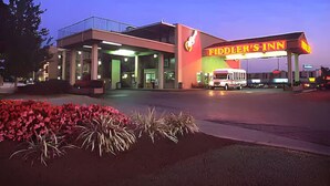 A hotel entrance with a neon sign reading "Fiddler's Inn" and a white van parked in front. - Fiddler's Inn (Nashville)