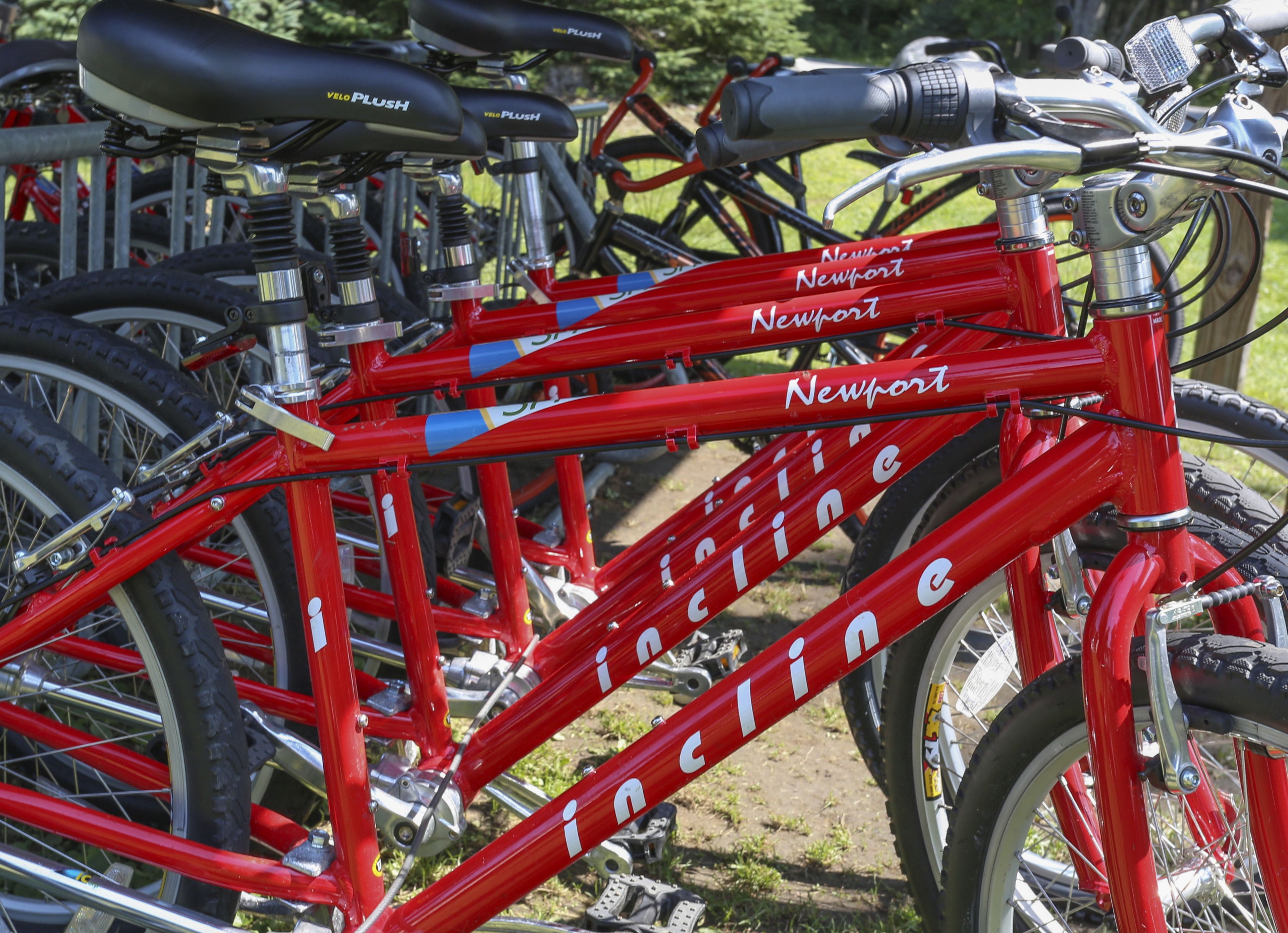 A red bicycle with "Newport" and "incline" written on it, parked among other bicycles.