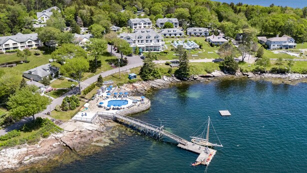 An aerial view of a lakeside resort with a dock, swimming pool, and multiple buildings.