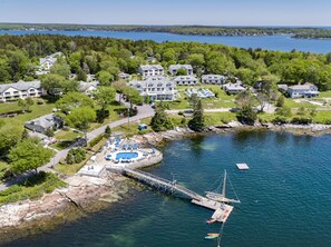 An aerial view of a lakeside resort with a dock, swimming pool, and multiple buildings. - Spruce Point Inn (Boothbay Harbor)
