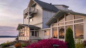 A two-story house with a balcony, large windows, and a view of the water. - Spruce Point Inn (Boothbay Harbor)