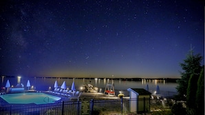 A swimming pool area at night with a clear view of the stars, a dock, and a small shed. - Spruce Point Inn (Boothbay Harbor)
