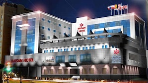 A modern hotel building with multiple floors, a prominent sign for Baisan Hotel, and a flag on top. - Baisan International Hotel (Manama)