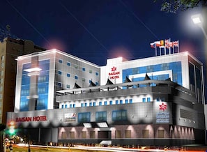 A modern hotel building with multiple floors, a prominent sign for Baisan Hotel, and a flag on top. - Baisan International Hotel (Manama)