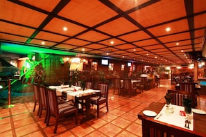 A restaurant with a tiled floor, wooden tables and chairs, and a grid-patterned ceiling. - Baisan International Hotel (Manama)