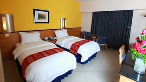 A hotel room with two beds, a desk, a chair, a small table, and a curtain. - Baisan International Hotel (Manama)