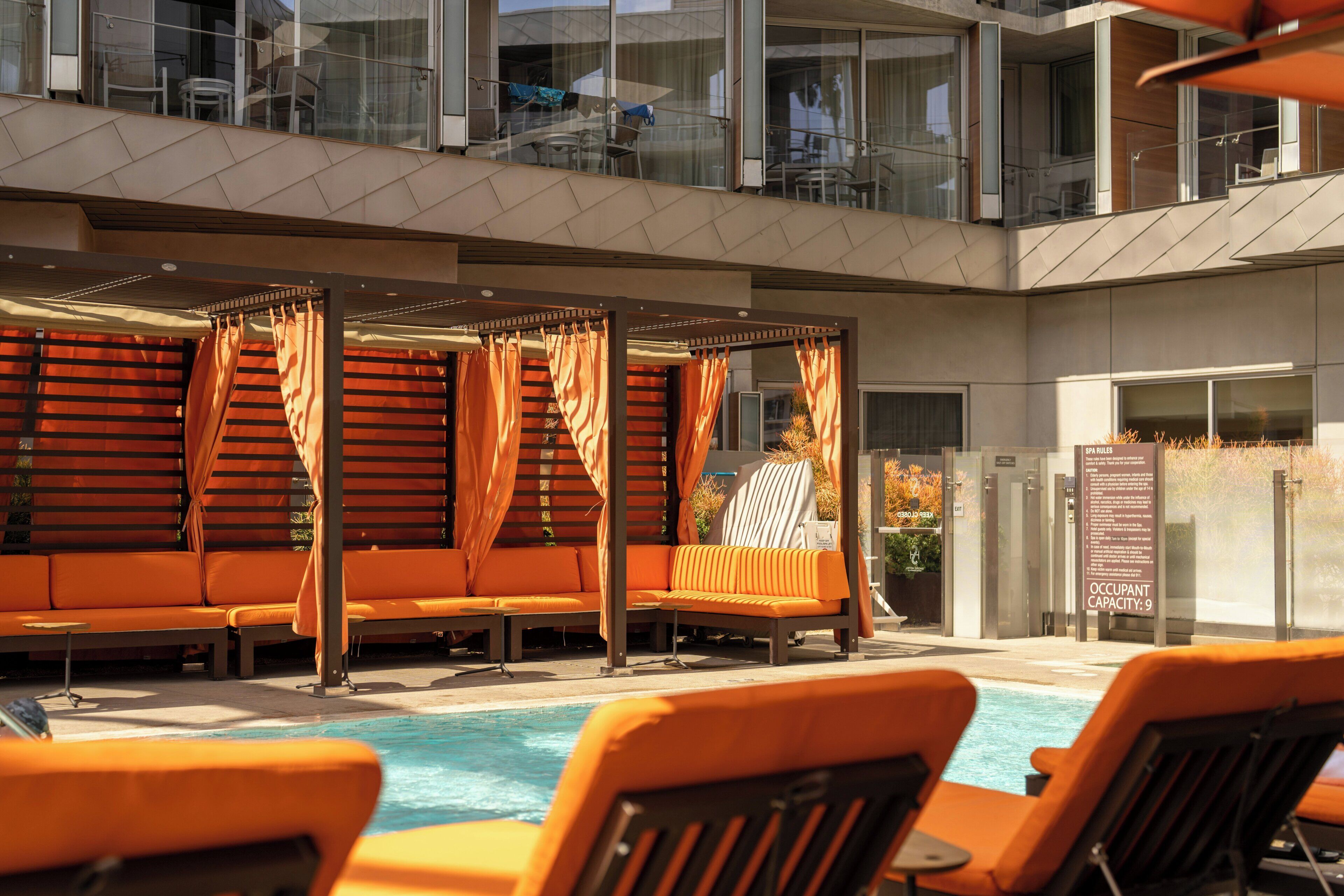 Un espace aménagé au bord de la piscine, avec des sièges orange et une partie abritée.