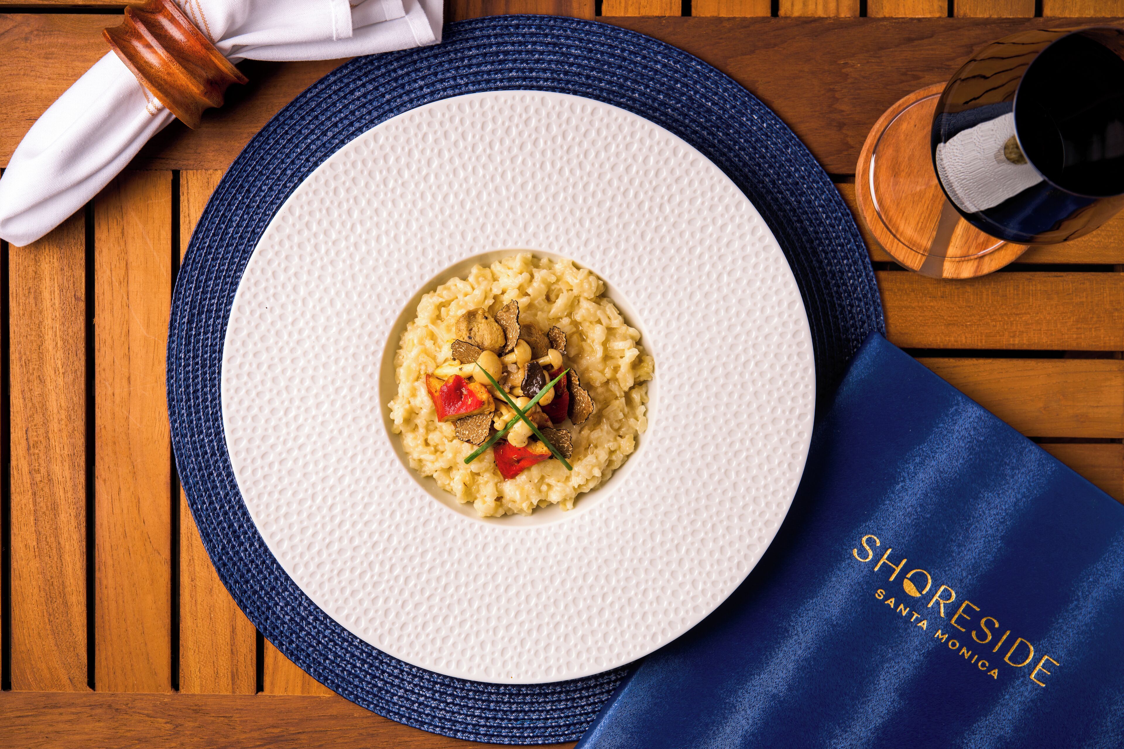 A plate of food on a wooden table with a placemat and a napkin.