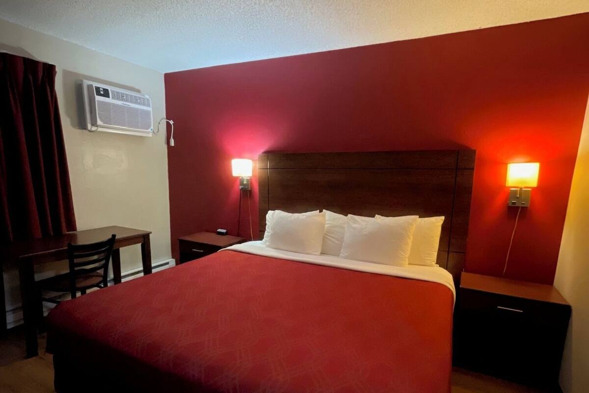 Una habitación de hotel con una cama grande, un escritorio y dos mesitas de noche.
