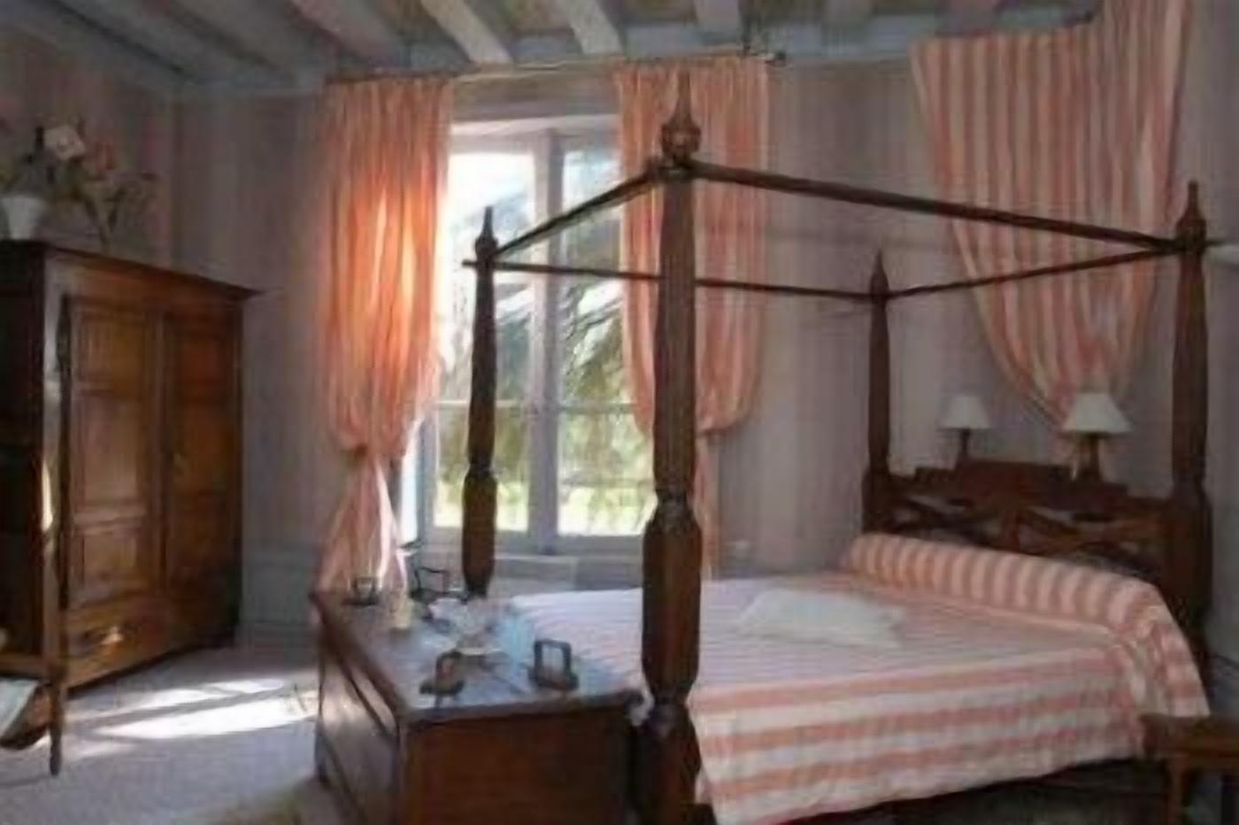 A four-poster bed with a wooden frame, a bedside table, and a dresser.