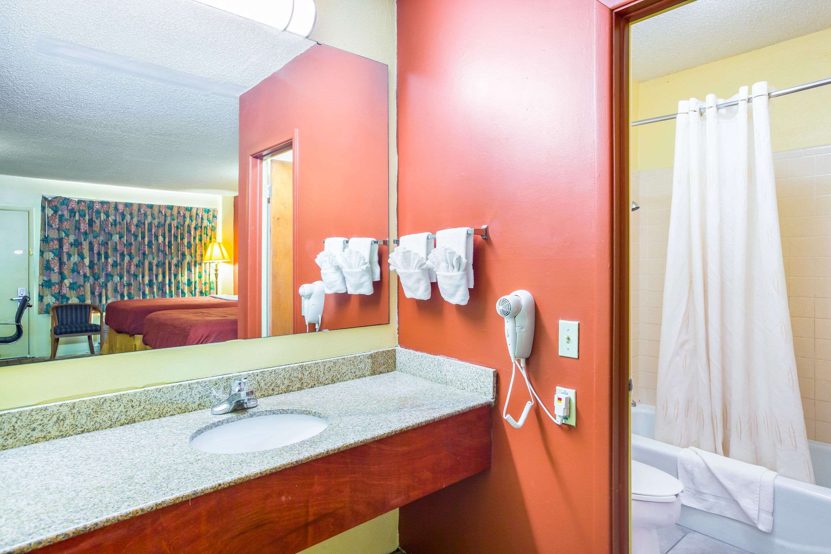 A bathroom with a sink, a hairdryer, and a shower curtain.