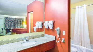 A bathroom with a sink, a hairdryer, and a shower curtain.