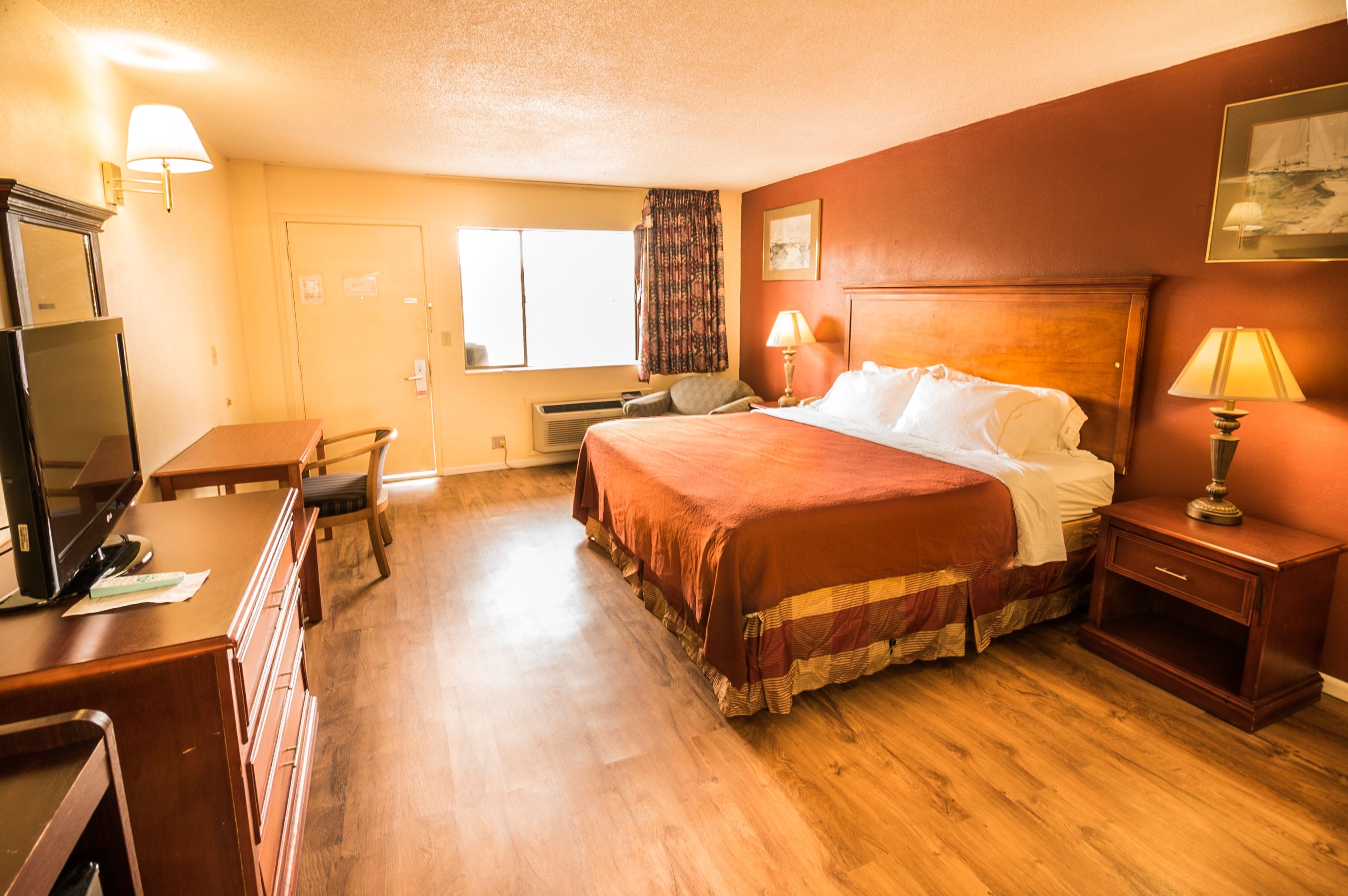 A hotel room with a bed, desk, chair, and a television.