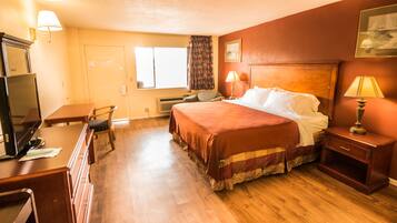 A hotel room with a bed, desk, chair, and a television.