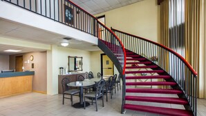 A hotel lobby with a red carpeted staircase, a reception desk, and a dining area with tables and chairs. - Rodeway Inn Bonifay (Bonifay)