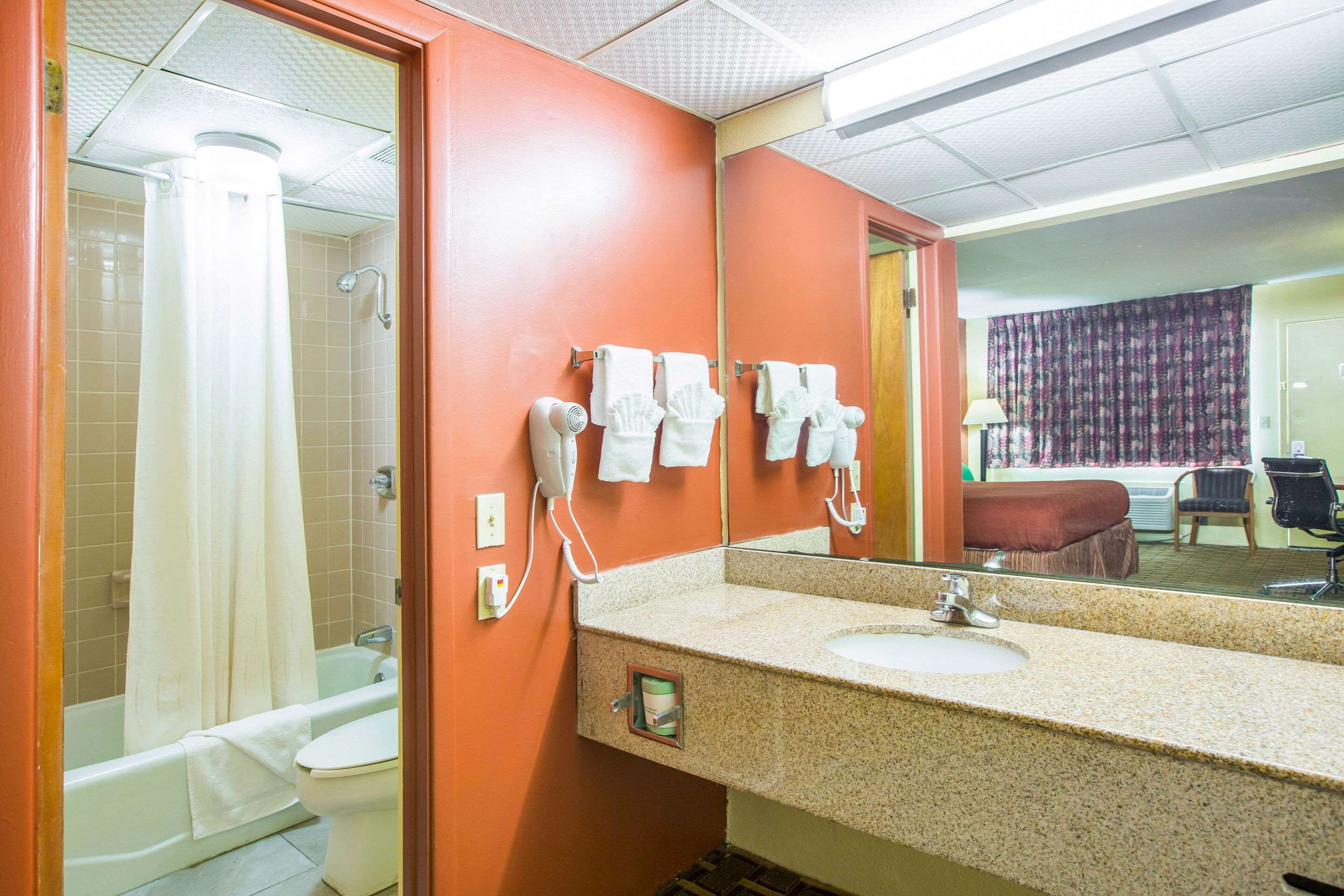 Een badkamer met een wastafel, spiegel en handdoekhouder.