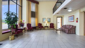 A spacious lobby with a large window, a potted plant, multiple seating areas, and a staircase. - Rodeway Inn Bonifay (Bonifay)