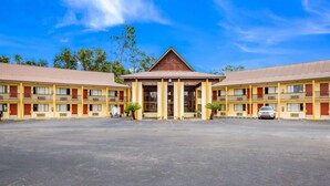 A motel with a central building flanked by two wings, featuring a symmetrical facade, large windows, and a parking lot in front. - Rodeway Inn Bonifay (Bonifay)