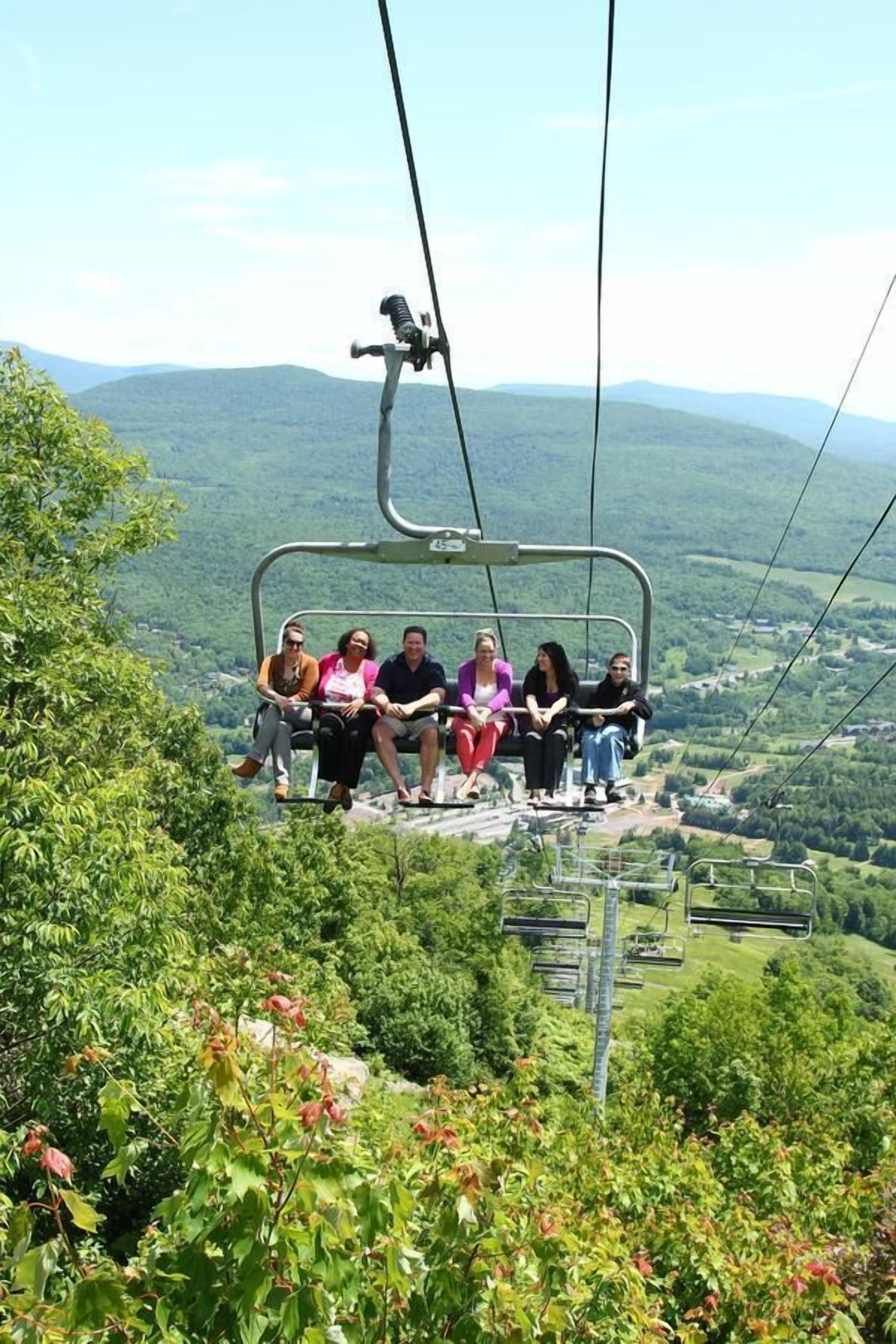 Un grupo de personas en un teleférico con un paisaje montañoso al fondo.