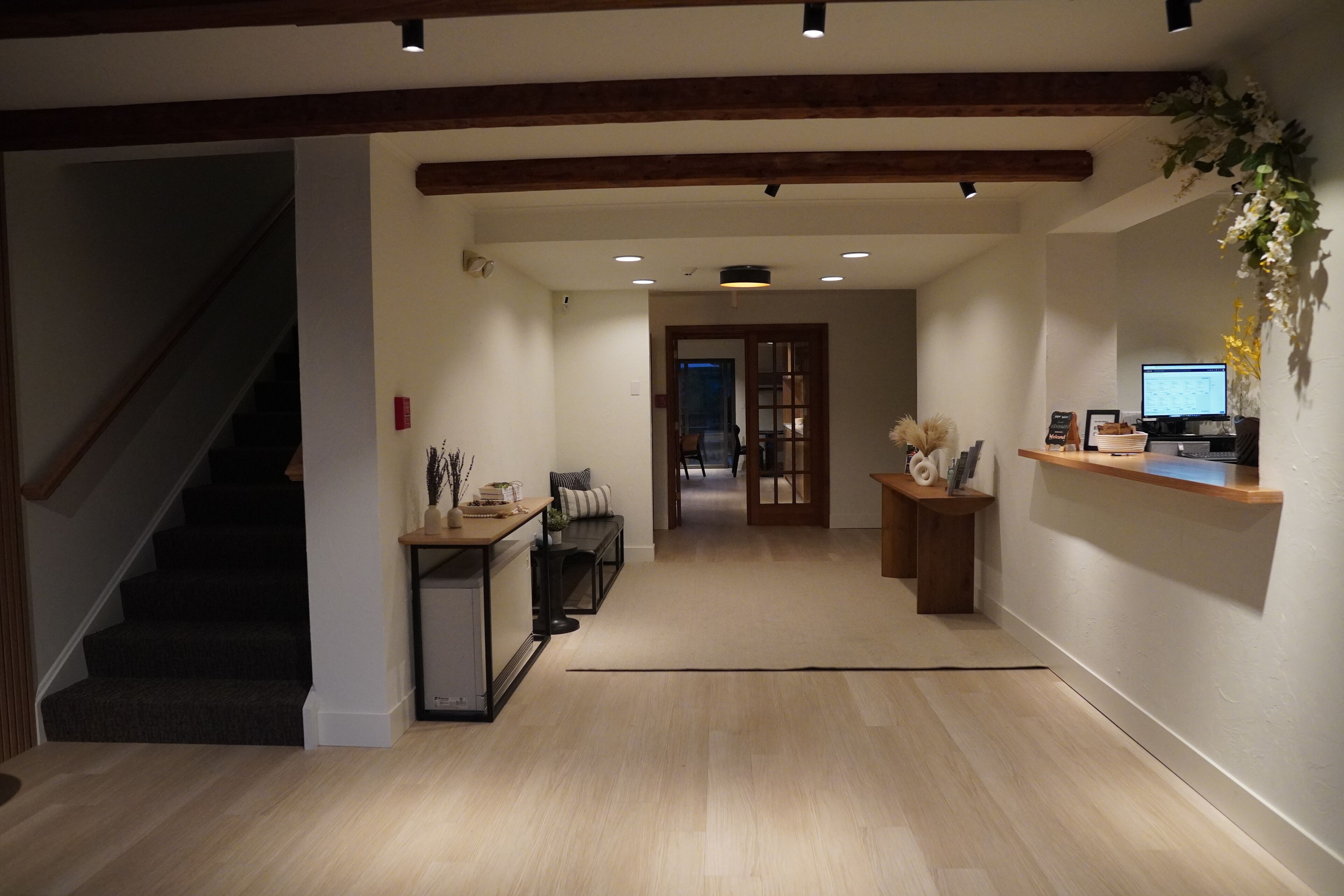 A spacious hallway with a staircase on the left, a reception desk on the right, and a door leading to another room in the center.