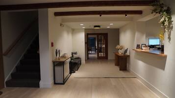 A spacious hallway with a staircase on the left, a reception desk on the right, and a door leading to another room in the center.