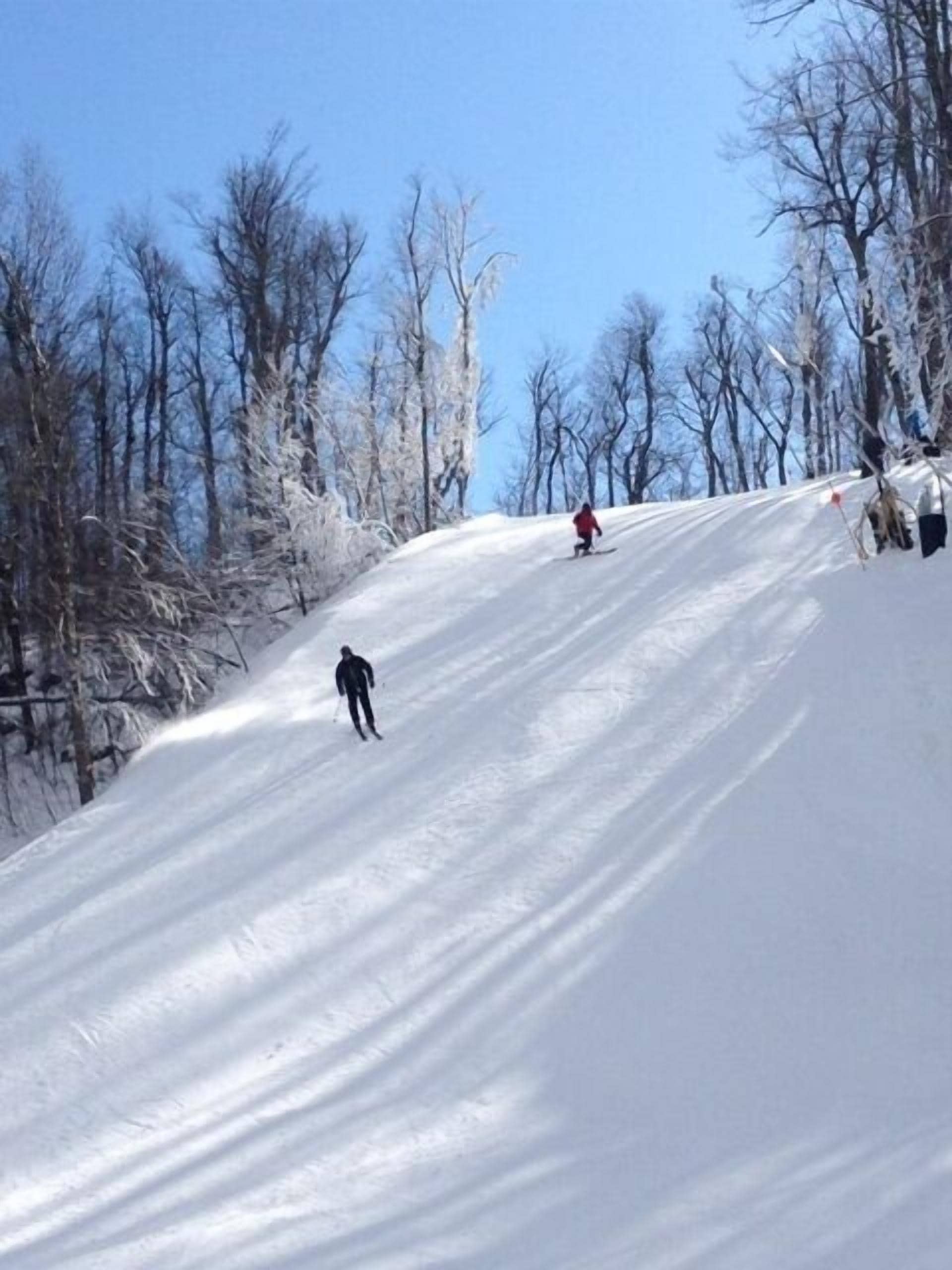A snowy ski slope with skiers.