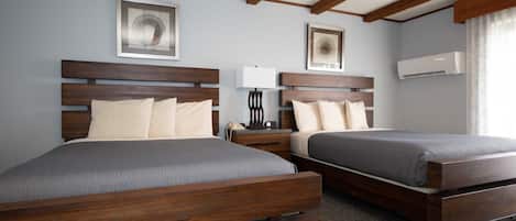 Habitación de hotel con dos camas de madera, una mesita de noche con lámpara y obras de arte en las paredes.