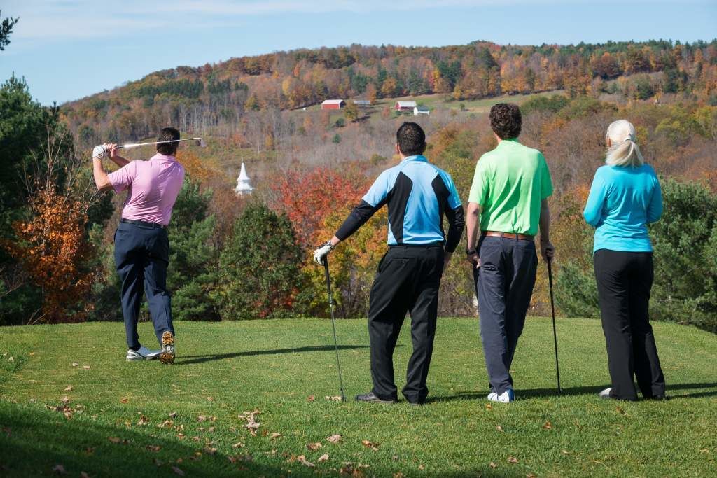 Un campo de golf con jugadores con diferentes vestimentas.