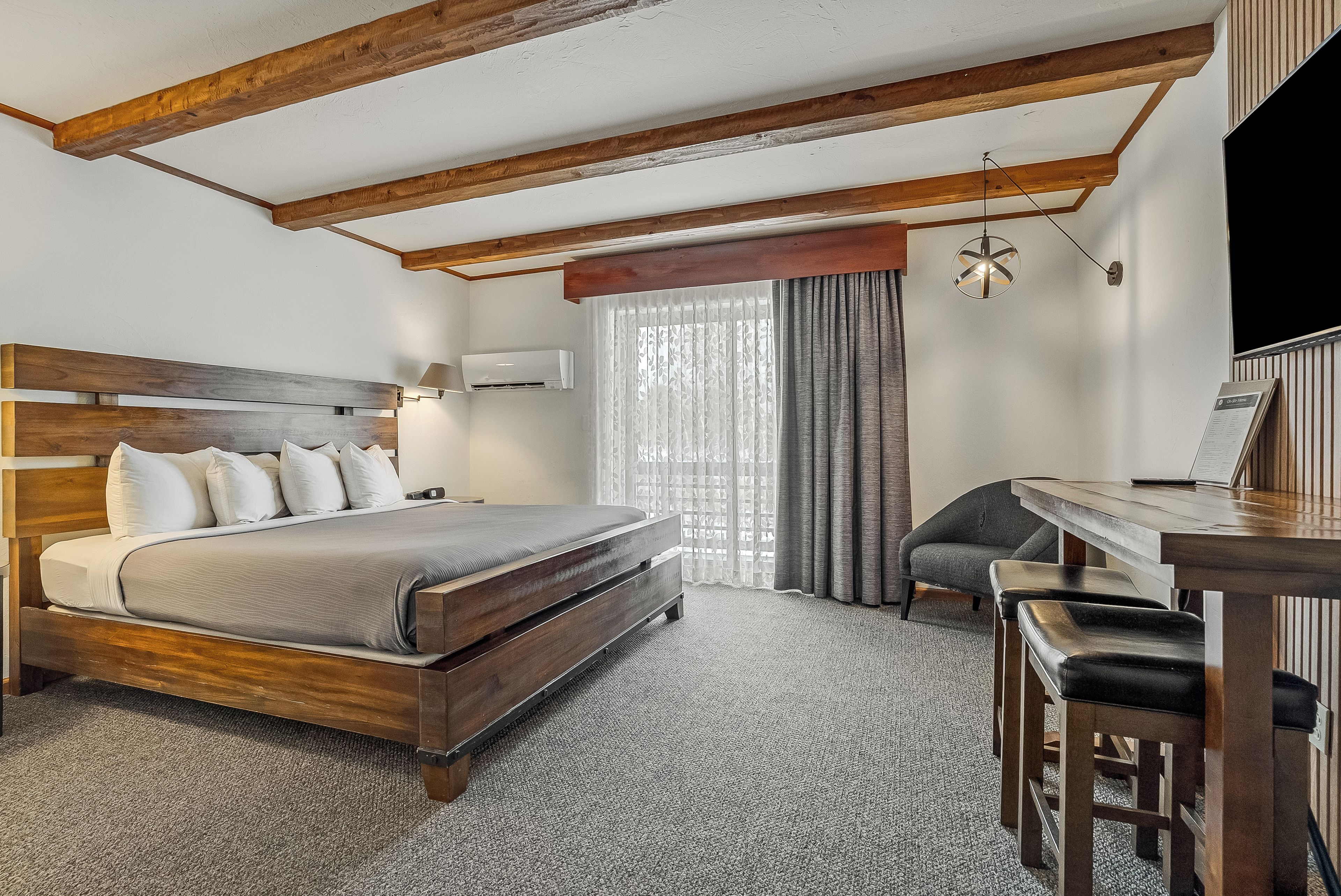 A hotel room with a wooden bed, a desk, and a chair.