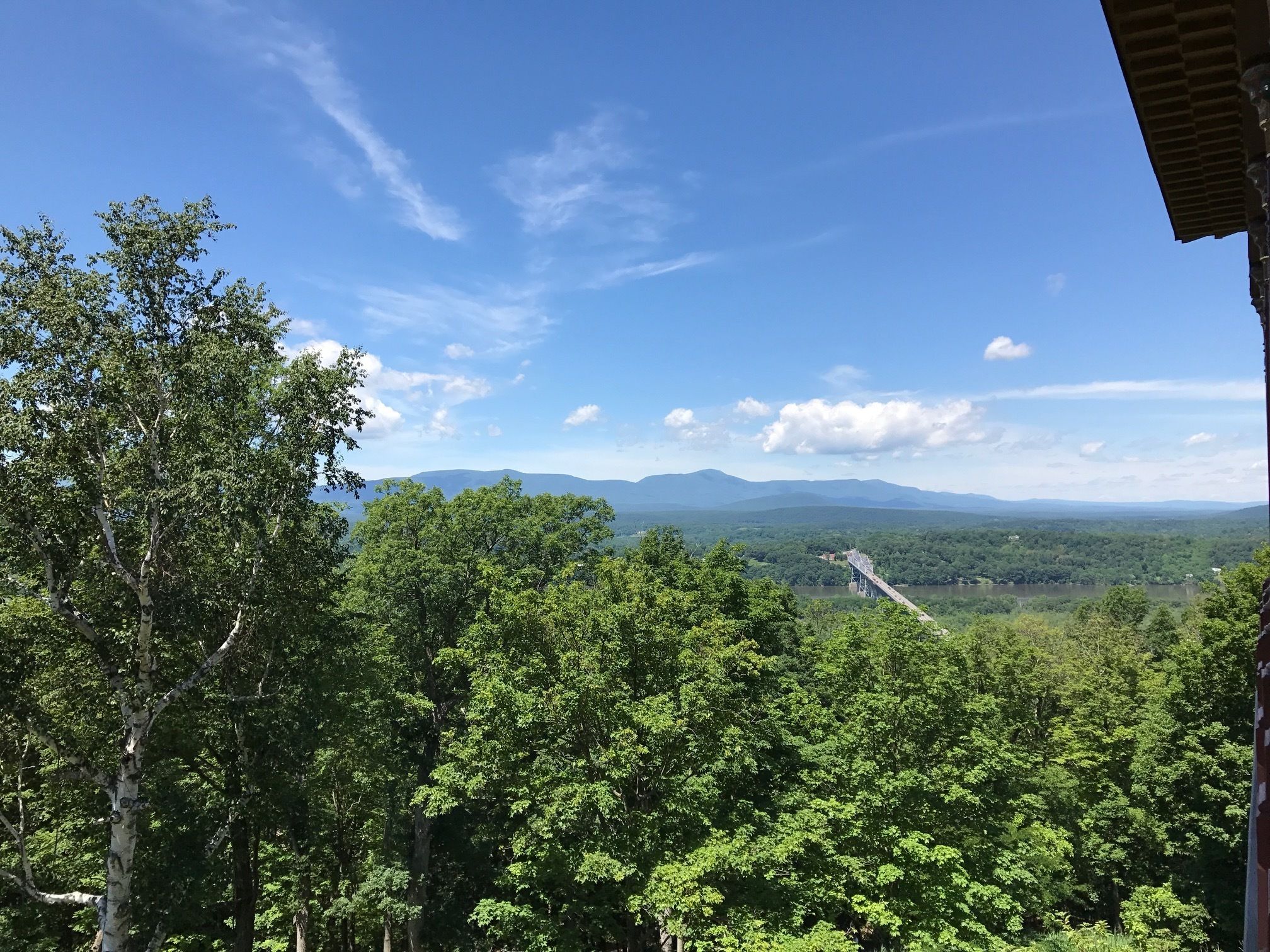 A view of a forested landscape with a bridge and distant mountains.