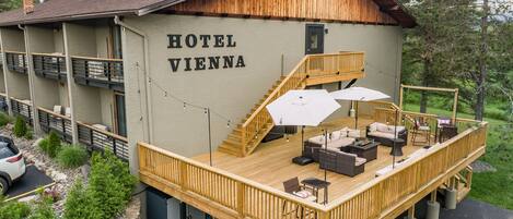 A hotel with a wooden deck, outdoor seating, and a staircase leading to the upper level.