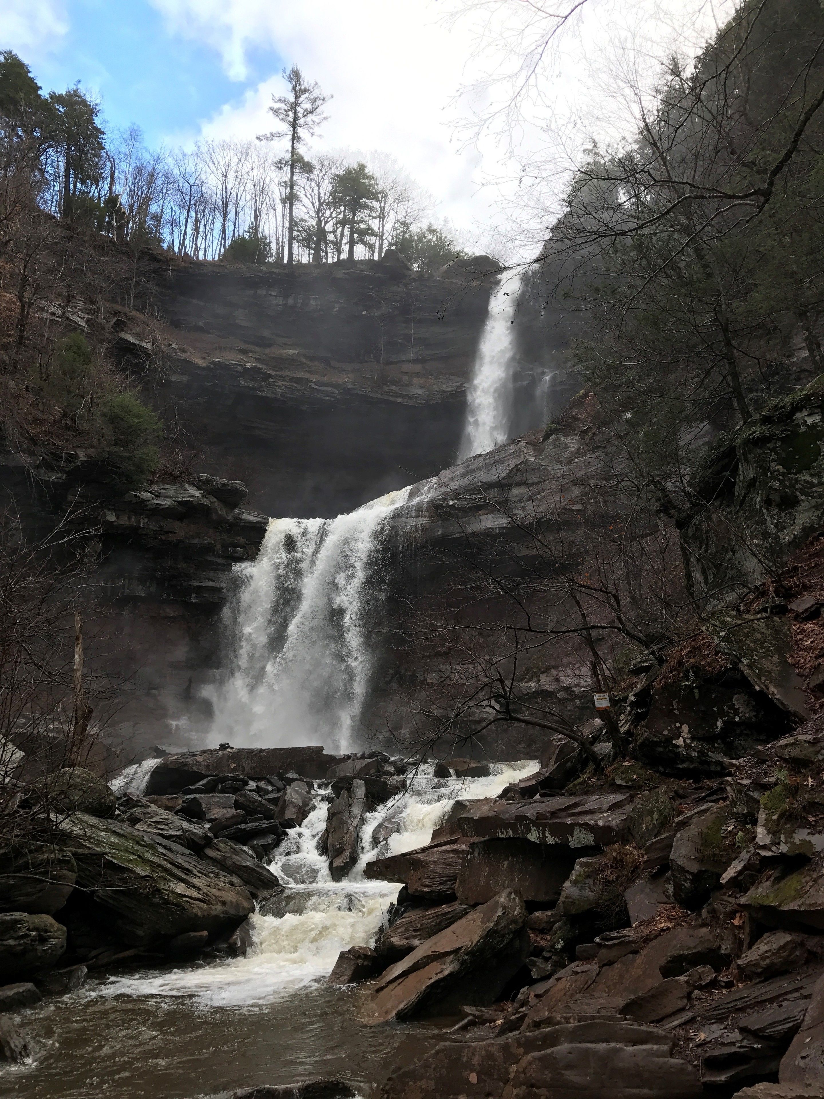 A waterfall cascading over rocky terrain surrounded by trees.