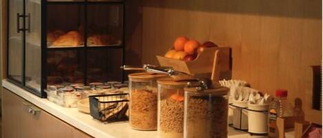 Una cocina con armarios de madera, una vitrina de vidrio con pan y diversos alimentos sobre la encimera.