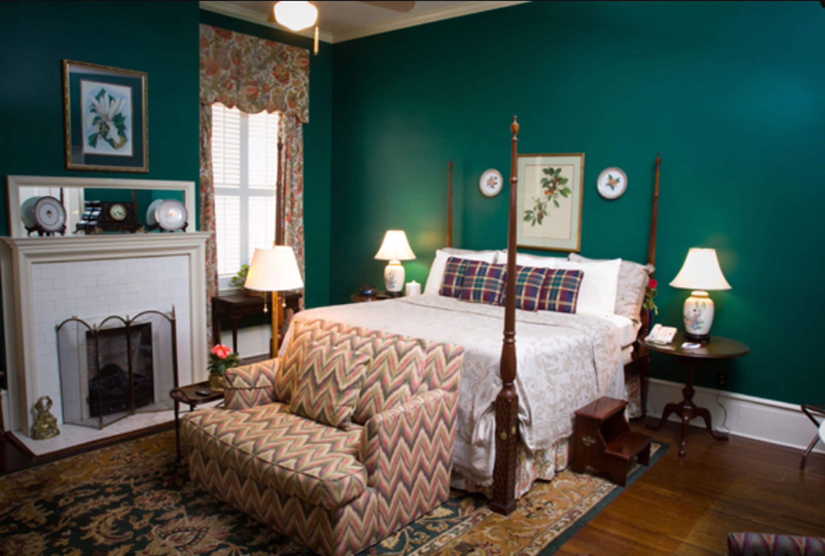 A bedroom with a four-poster bed, a fireplace, and a sofa.